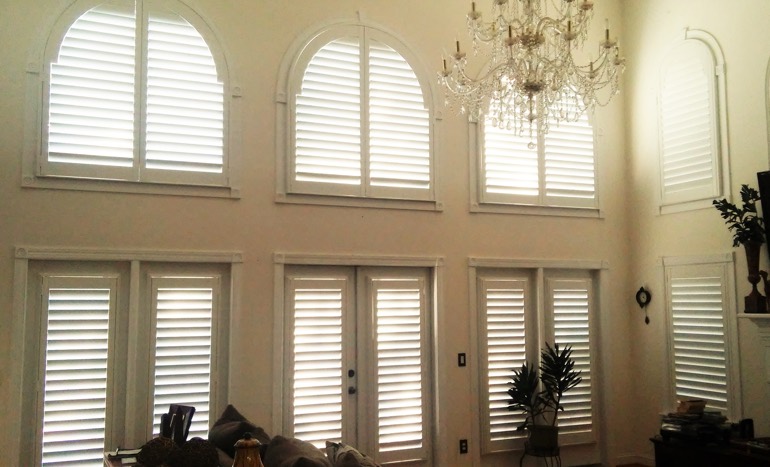 Television room in two-story Indianapolis house with plantation shutters on high windows.