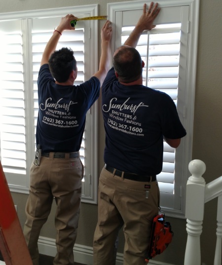 Two Sunburst Shutters technicians installing plantation shutters