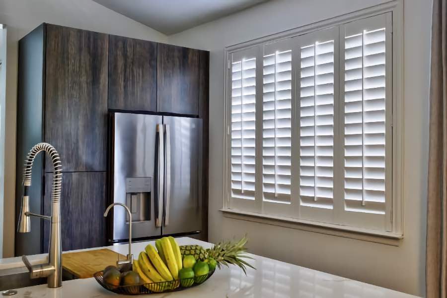 Homeowners use indoor window shutters in Indianapolis when they want attractive and functional window treatments. Polywood shutters on a large kitchen window