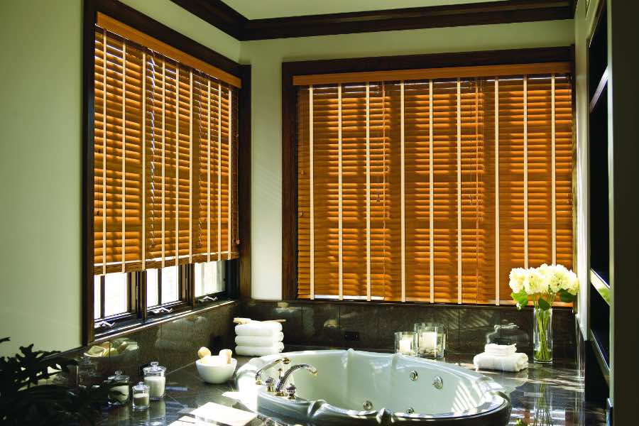 Premium quality blinds are always a stylish accent in your Indianapolis home. Brown wood blinds on large windows in a green bathroom