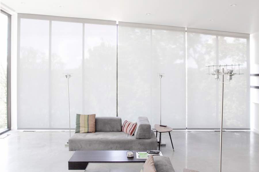 Motorized window shades make controlling natural light effortless in your Indianapolis great room. White motorized shades on a wall of tall great room windows