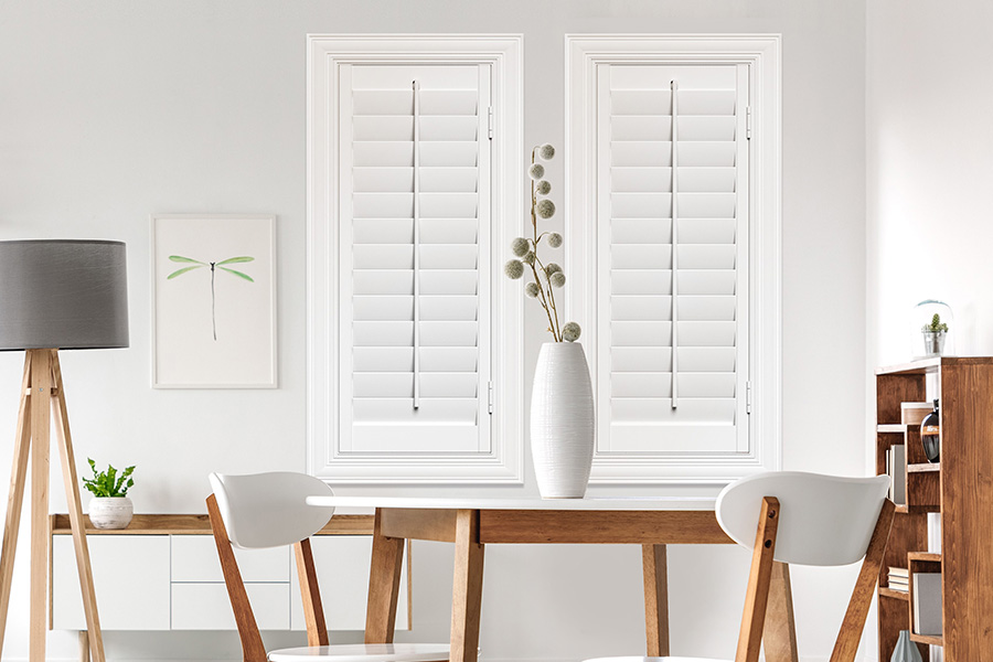 Sunburst's selection of stylish window treatments for designers in Indianapolis makes it easy to find the perfect ones for every design job.  White Polywood shutters on two windows in a modern Scandinavian-style room