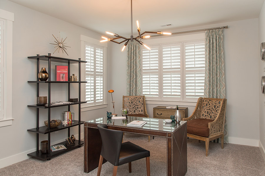 Colorful curtains can add a bit of flair with white Polywood shutters in Indianapolis. Sage green patterned curtains on white polywood shutters in an office.