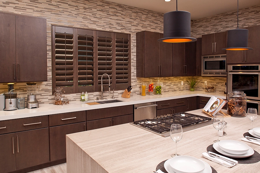 With many on-trend colors to choose from, you can find Ovation shutters in hues that match or coordinate with your existing home decor. Dark wood Ovation shutters on a kitchen window with matching cabinetry