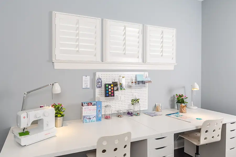 Small windows, big impact: three Polywood shutters bring clean, uniform style to this cheerful craft space. 3 small white shutters in a row above a craft and art desk area